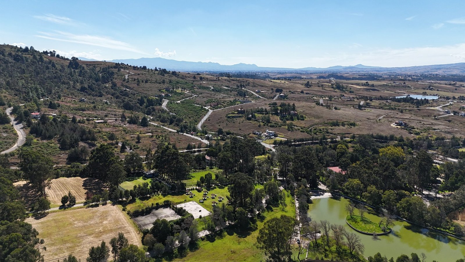 Vista aérea del desarrollo residencial La Purísima con vialidades, bosque y lago